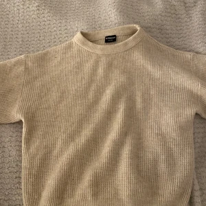 Beige stickad tröja från Firefly - Säljer en stilren beige stickad tröja från Firefly. Tröjan har en rund halsringning och korta den har korta ärmar. Den ribbade strukturen ger en klassisk look. Passar både till vardags och mer avslappnade tillfällen. Skriv för bilder på. ❤️