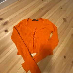 Orange ribbad kofta - Säljer en snygg orange ribbad kofta med knyt framtill. Den har långa ärmar och en croppad passform, med mycket urringning. Skriv för fler bilder💗 köparen står för frakt!