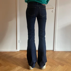 Mörkblå bootcut jeans - Säljer ett par snygga mörkblå bootcut jeans. De har en klassisk femficksdesign och är perfekta för både vardag och fest. Jeansen är i bra skick och har en skön passform som sitter snyggt över höfterna och släpper ut i en bootcut-stil vid benen.