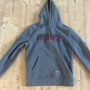 Säljer en snygg grå hoodie från Hoodrich. Den har en stor ficka fram och en bekväm huva. Perfekt för en avslappnad stil eller för att hålla sig varm under kyliga dagar. Passar både till vardags och chillk