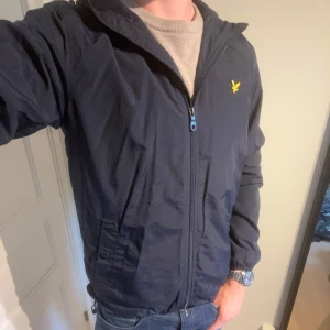 Windbreaker jacka - En marinblå windbreaker från Lyle & skott. Riktigt fet och unik. Passar bra nu i höst. Ny kostar 1000kr. Vårt pris är bara 599kr. Är i nyskick. Kontakta oss vid frågor! 