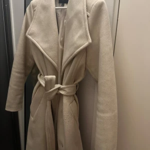 Beige kappa - En otroligt fin beige kappa från Vero Moda i strl 38 men skulle även passa en 36, köpt förra vintern.  Den är  nopprig vid fickorna, men hade säkert gått att fixa med en rakhyvel, eller apparat för det, därav priset!
