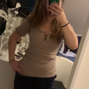 Figuranpassad t shirt - Säljer denna superfina och unika figursydda tröja, den har blomdetaljer på ryggen och mellan knapparna💞 Nyskick och inga defekter från Garden Girl❤️ Den är mest beige och lite brun i färgen. Storlek M, och jag själv brukar ha S i kläder