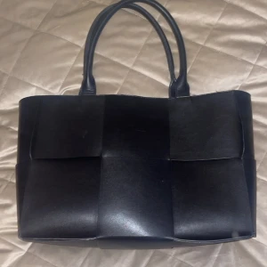 Svart skinväska medelstor - Medelstor svart väska i skin med gulddetaljer och stort utrymme. 