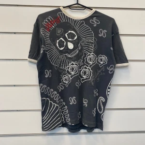 Billabong Skull T-Shirt y2k - Grå t-shirt med snyggt tryck på framsidan med rosor o skallar. Ifrån märker Billabong  I bra skick med inga defekter  Storlek Medium  Skriv ifall du har några fler frågor!