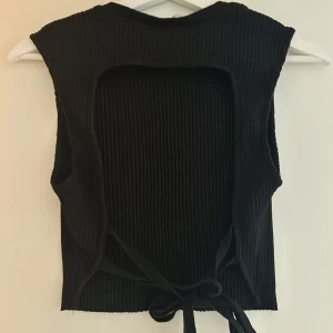 Svart topp - Svart ribbad topp från zara, öppen rygg. Använd en gång. 