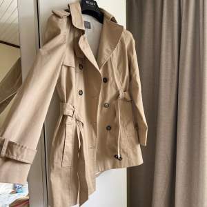 Klassisk trenchcoat i beige färg. Perfekt i längden. Den är i väldigt bra skick. 