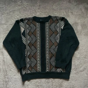 Mönstrad stickad tröja - Säljer en unik och mysig stickad tröja med ett coolt geometriskt mönster i svart, brunt och beige. Perfekt för höst och vinter med sina långa ärmar och bekväma passform. Den är både stilren och varm, perfekt för kalla dagar!