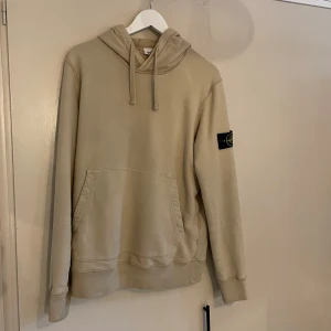 Stone Island hoodie - Hej! Säljer nu min stone Island hoodie som är beige och i fint skick, 7/10. Det är små hål i kanterna på magfickan. Skriv om det är något ni funderar över