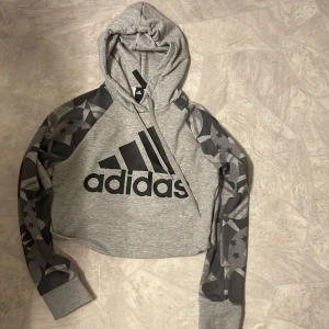 Croppad hoodie - Nästan helt oanvänd. Mönstrad på ärmarna och baksida, adidas logga på framsidan. 