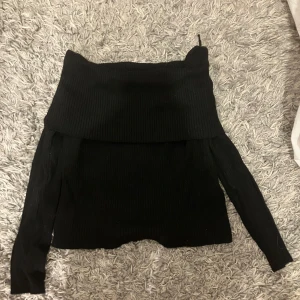 Svart ribbad offshoulder tröja från H&M - Säljer en snygg svart ribbad offshoulder tröja från H&M. Perfekt för en stilren look, med långa ärmar och en bekväm passform. I stl M, endast testad, köpte för 200 och säljer för 70! Perfekt tröja för hösten.