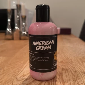 American cream shower gel Lush - En rosa duschgel från Lush med namnet 'American Cream'. Den har en krämig konsistens och en söt doft som påminner om vanilj och jordgubbar. Perfekt för att göra huden mjuk och väldoftande efter duschen. Aldrig använd, endast doftat på den.