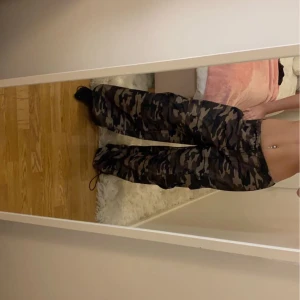 Camouflage cargobyxor - Säljer ett par snygga camouflage cargobyxor i loose fit. Perfekta för en avslappnad stil med praktiska fickor på sidorna. Byxorna har en elastisk midja med dragsko för bästa passform. Superbekväma och trendiga för vardagsbruk! Oanvänd. Passar storlek xs- m/L