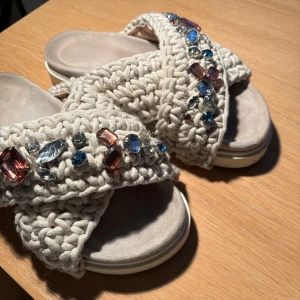 Beige sandaler med pärlor - Säljer ett par supercoola beige sandaler med korsade remmar i stickat material. De är dekorerade med färgglada pärlor i olika former och storlekar. Perfekta för sommaren! Original pris 2599kr