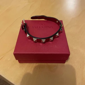 Valentino armband rött - Fett armband från valentino. Bra sick. Finns lite slitningar på undersidan som man ser på sista bilden. Men syns inte på😀. Finns extra nitar. Hör av dig vid funderingar🤝tar emot byten