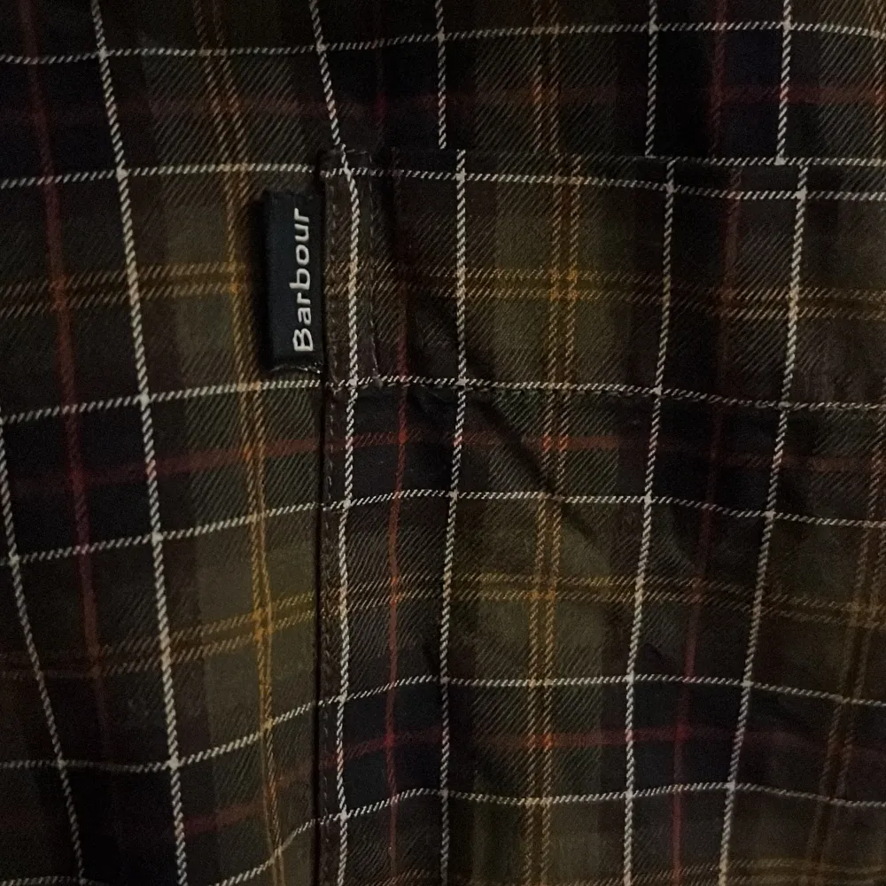 Säljer en snygg rutig skjorta från Barbour i mörka toner. Skjortan har en stilig bröstficka på vänstersidan. Perfekt för höst och vinter med sitt klassiska mönster och bekväma passform. Den är i mycket bra skick och passar både till vardags och lite finare tillfällen. Nypriset för denna skjorta är 1200kr. Skjortor.