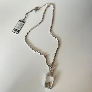 Äkta silver halsband med kristallhänge från Joop - Snyggt silverfärgat halsband med ett unikt kristallhänge. Hänget har en cool geometrisk form och kedjan är i en stilren design. Perfekt för att ge en extra touch till din outfit, oavsett om det är till vardags eller fest. Ett måste för smyckesälskare! Aldrig använt!