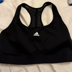 Svart sport-bh från Adidas - Säljer en svart sport-bh från Adidas i mycket bra skick. Den har en klassisk design med brottarrygg och elastiskt band med Adidas-logga. Perfekt för träning och ger bra stöd. Passar till alla typer av sportaktiviteter.