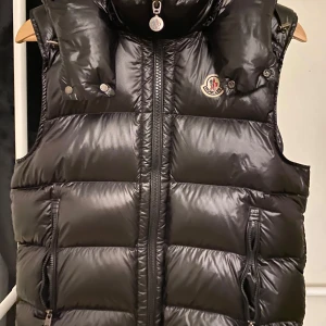 BORMES DOWN GILET/ MONCLER väst/ Size 1 - Upptäck den exklusiva BORMES DOWN GILET från Moncler, storlek 1 - en perfekt kombination av stil och funktionalitet. Denna gilet är tillverkad av högkvalitativa material och erbjuder en lättviktig men värmande design, idealisk för både stadsbruk och 