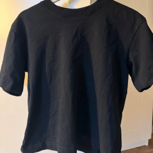 Svart t-shirt från Gina Tricot - Säljer en klassisk svart t-shirt från Gina Tricot i storlek S. Den är i bomull och har en normal passform med korta ärmar. Perfekt basplagg för alla tillfällen! 🖤