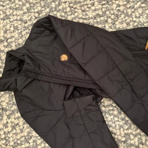 Svart lång Fjällräven jacka - Säljer en svart lång jacka från Fjällräven i mycket bra skick. Jackan är quiltad och har en dragkedja framtill. Perfekt för höst och vinter med sin varma och stilrena design. Passar bra till både vardag och utomhusaktiviteter. Skriv privat för bättre bilder 