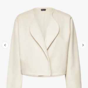 Vit kappa från Gina tricot  - Säljer en stilren vit kavaj från Mango. Den har en elegant, croppad design med långa ärmar och en öppen framsida utan knappar. Perfekt för både vardag och festliga tillfällen. Passar bra till både jeans och klänning!