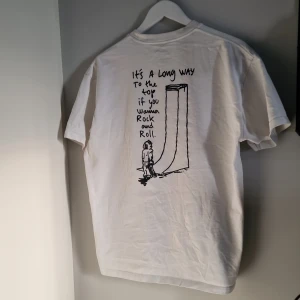 Vit t-shirt från Polar Skate Co. - Säljer en vit t-shirt från Polar Skate Co. med ett coolt tryck på baksidan som säger 'It's a long way to the top if you wanna rock and roll'. Perfekt för vardagsbruk eller skate. T-shirten är i bra skick och har en normal passform. Små fläckar längst ner på framsidan även en ljusbeige fläck som knappt syns. Se bild noga. 