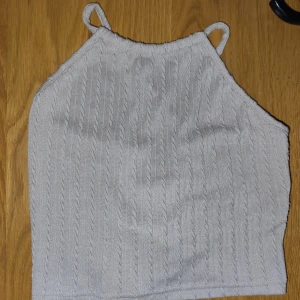 Beige ribbad linnetopp - Säljer en superfin beige ribbad linnetopp med smala axelband. Toppen har en snygg snörning i ryggen som ger en unik look. Perfekt för sommardagar eller en avslappnad kväll ute. Materialet är mjukt och stretchigt för en bekväm passform.