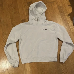Vit hoodie från NA-KD - Säljer en stilren vit hoodie från NA-KD i storlek M. Hoodien har en klassisk design med en liten logga på bröstet. Perfekt för både vardag och mysiga hemmakvällar. 