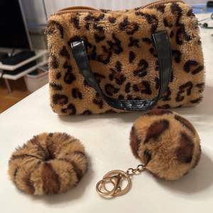 Säljer en supercool leopardmönstrad väska i fluffigt material med svarta handtag. Väskan har en dragkedja upptill och är perfekt för att ge din outfit en vild touch. Medföljer gör en matchande scrunchie och en fluffig nyckelring. Perfekt för höst och vinter!