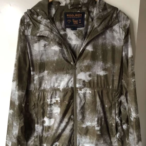 Camouflage vindjacka från Woolrich - Säljer en cool camouflage vindjacka från Woolrich. Perfekt för höst och vår när vädret är lite osäkert. Jackan är i mycket bra skick och har en unik mönsterdesign som verkligen sticker ut. Jackan är M/L men sitter mer som S/M
