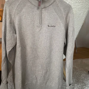 Stickad tröja från Bondelid - Säljer en stilren sticka tröja från Bondelid i mycket bra skick. Den har en halv dragkedja och ribbade detaljer vid kragen och ärmsluten. Perfekt för både höst och vinter, och funkar lika bra till vardags som till lite finare tillfällen.
