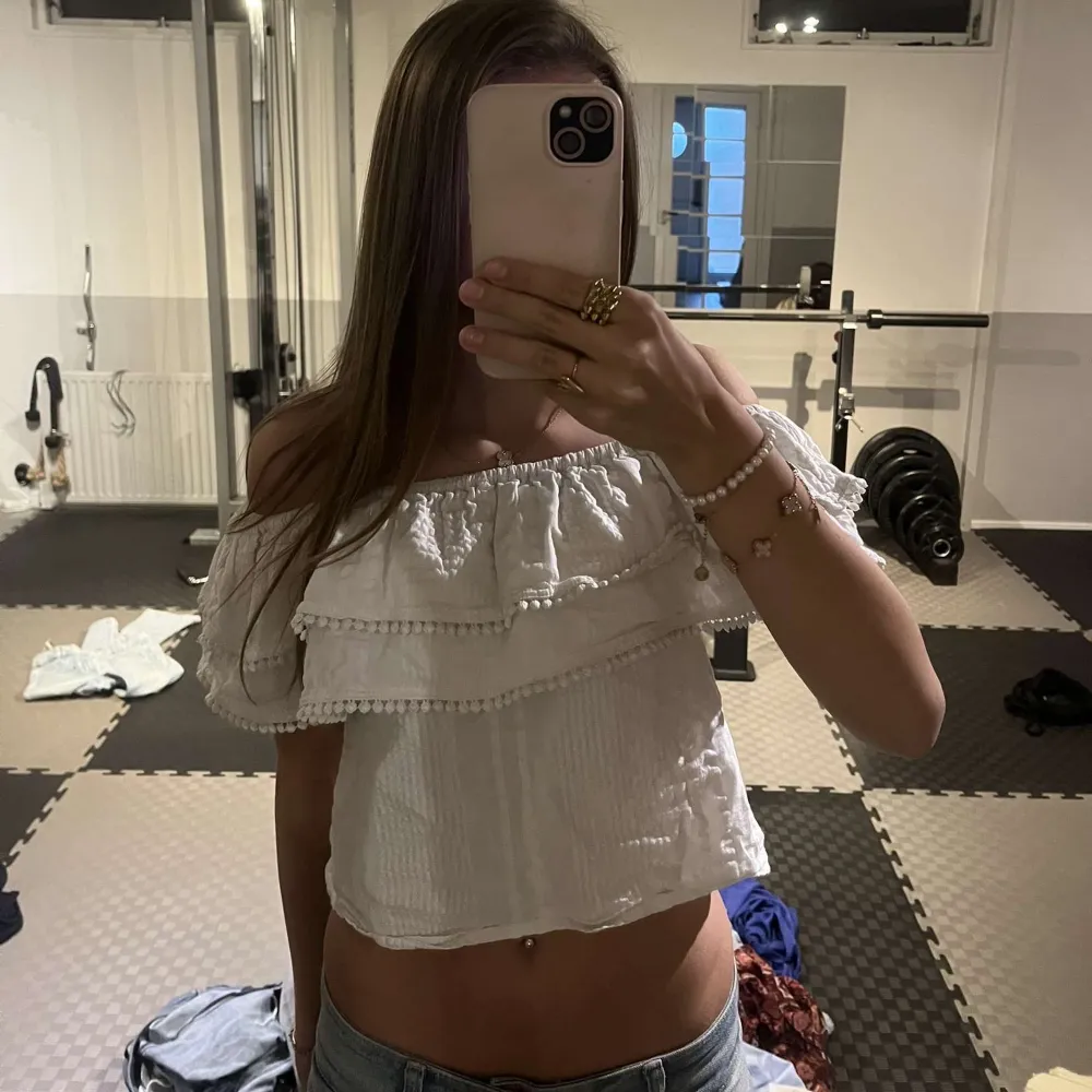 Säljer en superfin vit offshoulder topp med volanger. Den är perfekt för sommaren och har en croppad passform som ger en snygg look. Toppen är i bra skick och passar perfekt till jeans eller kjol för en avslappnad stil.. Toppar.