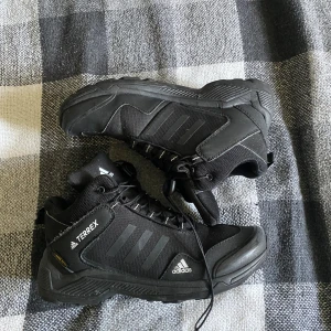  Adidas Terrex boots - Säljer ett par svarta Adidas Terrex boots i bra skick. Perfekta för utomhusaktiviteter med robust sula och snörning för extra stöd. De är gjorda i syntetmaterial och har en sportig look. Passar bra för höst- och vinterväder.