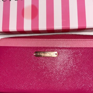 Rosa plånbok från Victoria's Secret oanvänd, limeted kostade 1000kr ny - Säljer en superfin rosa plånbok från Victoria's Secret. Den har en snygg glansig finish och en dragkedja upptill. Perfekt för att hålla ordning på kort och kontanter. Kommer i en söt randig presentförpackning. Perfekt som present eller till dig själv!