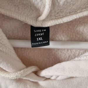 Beige hoodieklänning från Shein Curve - Mysig beige hoodieklänning från Shein Curve i storlek XXL. Perfekt för en avslappnad dag hemma eller en promenad i parken. Den har texten 'OVERTHINKING' tryckt på framsidan och långa ärmar med muddar. Superbekväm och stilren!