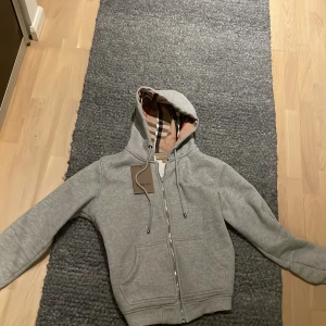 Grå burberry hoodie L - Jag säljer min burberry hoodie i storlek L eftersom jag växt ur den. Den är liten i storleken så den kan passa M också. Köptes på plick för ett år sedan. använt fåtal gånger. Mitt pris är förhandlingsbart