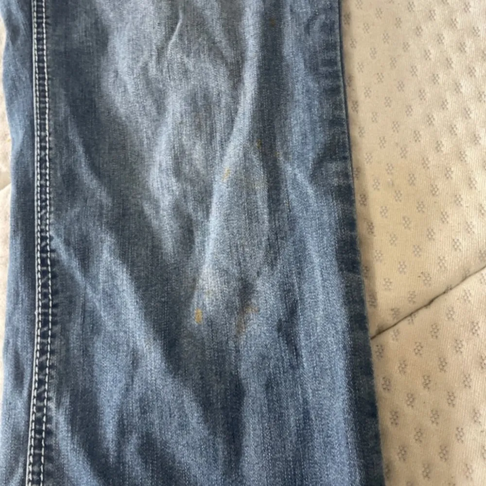 Säljer ett par snygga blå jeans med unika broderade detaljer på bakfickorna. De har en bootcut-stil och är perfekta för en avslappnad look. Jeansen har en fläck som knappast syns. Midjemått: 43cm Innerbenslängd: 79cm skickar inga bilder på !. Jeans & Byxor.