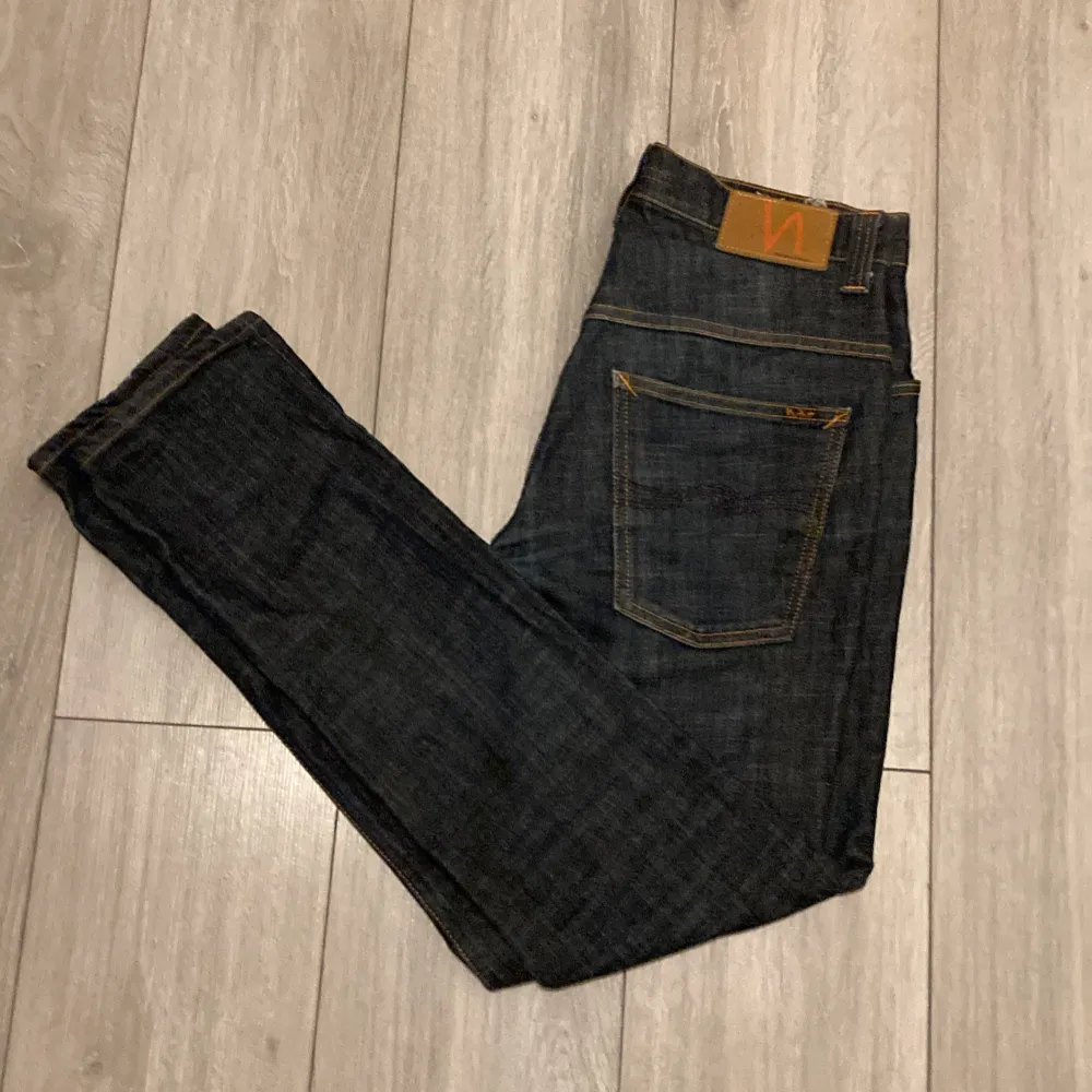 Säljer ett par snygga mörkblå jeans från Nudie Jeans i storlek W31 L32. De har en klassisk femficksdesign med orange sömmar och en bekväm passform. Perfekta inför vintern och är väldigt sköna och varma. Jeans & Byxor.