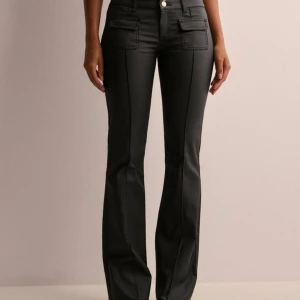 Coated low waist bootcut pocket jeans  - Säljer dessa as snygga jeans i skinn aktigt material, är coated. Är aldrig använda av mig utan endast provade! Säljer då jag inte tycker att dem sitter fint på mig. De är i storlek 40 men passar 40/38! Dessa är slutsålda på hemsidan!