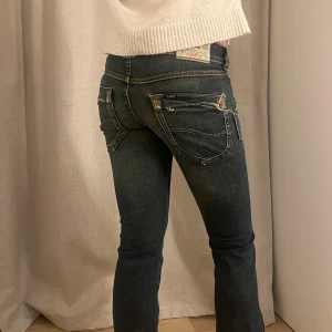 Mörkblå jeans med slitna detaljer - Säljer ett par otroligt unika mörkblå jeans i bra skick. De har en tight passform och är lågmidjade med coola slitna detaljer på fram- och baksidan. Perfekta för en avslappnad vardagslook eller en utekväll. Passar bra till en stickad tröja eller en t-shirt! Passar xs och s