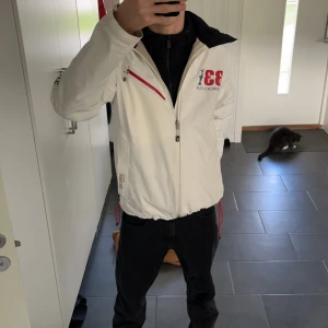 Regnjacka/sail jacka - Säljer en vit jacka från Peak Performance, designad för 33 America's Cup. Jackan har en dragkedja och flera praktiska fickor. Den är perfekt för vår och höst med sin stilrena look och funktionella design. Passar bra för både vardag och sportiga aktiviteter.har även en huva man kan fälla ut om man vill i färgen neon gul. Priset går själv klar att diskuteras