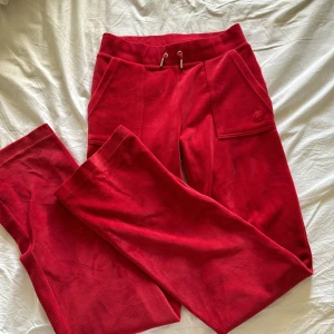 Röda mjukisbyxor från Juicy Couture - Säljer ett par snygga röda mjukisbyxor från Juicy Couture i storlek XS. Perfekta för en avslappnad dag hemma eller en chill dag ute. 🩷