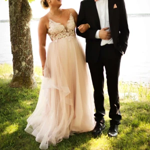 Rosa balklänning med spetsdetaljer - Denna Underbar rosa balklänning med spetsdetaljer och volanger. Klänningen har en vacker omlott-design och är ärmlös, perfekt för bal och fest. Den har en lång, flödande kjol som ger en elegant look. Passar s-m jag är 160 ungefär men den passar även längre då jag fick lyfta den lite.