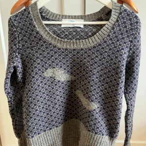 Mönstrad stickad tröja från Whyred - Säljer en snygg stickad tröja från Whyred i storlek S. Tröjan har ett unikt mönster i blått och grått med ribbade kanter vid hals, ärmslut och nederkant. Perfekt för kyliga dagar och ger en stilren look. Passar både till vardags och lite finare tillfällen.