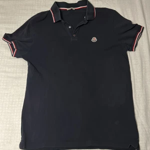 Moncler pike - Hej säljer min fina marinblåa moncler piké, skick 8/10. Skriv vid alla funderingar och vid pris förslag, priset är inte skrivet i sten!!