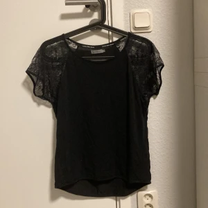 Svart topp från Calvin Klein Jeans - Snygg svart topp från Calvin Klein Jeans med korta spetsärmar. Perfekt för både vardag och fest. Toppen har en enkel och stilren design som gör den lätt att matcha med olika outfits. Fick av en släkting och har bara använts enstaka gånger.