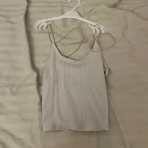 Vit ribbad linnetopp - Säljer en stilren vit ribbad linnetopp med smala axelband. Perfekt för sommardagar eller som ett basplagg i garderoben. Toppen har en enkel och klassisk design som passar till det mesta.