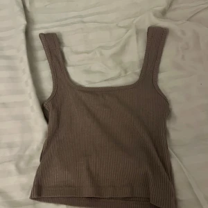 Brun ribbad linnetopp - Säljer en snygg brun ribbad linnetopp i mycket bra skick. Toppen är ärmlös och har en tight passform, perfekt för sommardagar eller som ett lager under en jacka. Den har en enkel och stilren design som passar till det mesta. Perfekt för både vardag och fest!