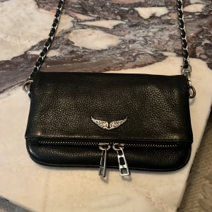 Zadig väska nano - Säljer min jättefina Zadig Voltaire väska som är andvänd men det syns inte, inga defekter på väskan. Dustbag ingår. Orginalpris ligger runt 2800. Kan tänka mig att gå ner i pris vid snabb affär.